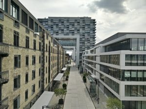 A vibrant urban street flanked by modern and historic buildings under a cloudy sky.