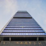 Stunning low angle view of a modern skyscraper with glass windows against a clear sky, highlighting architectural innovation.