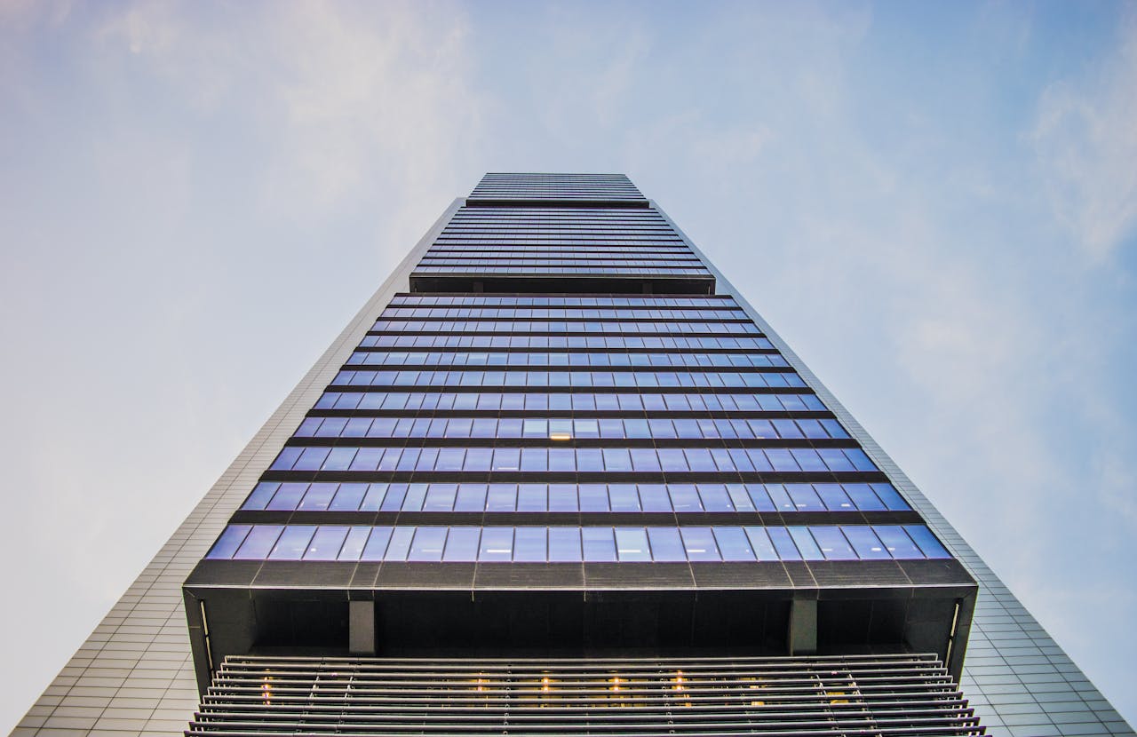 Stunning low angle view of a modern skyscraper with glass windows against a clear sky, highlighting architectural innovation.