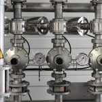 Close-up of stainless steel pipes with pressure gauges in an industrial setting.