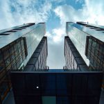 Low-angle view of sleek, modern skyscrapers with glass facades under a blue sky.