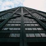 An upward perspective of a modern glass skyscraper against a cloudy sky in downtown Chicago.