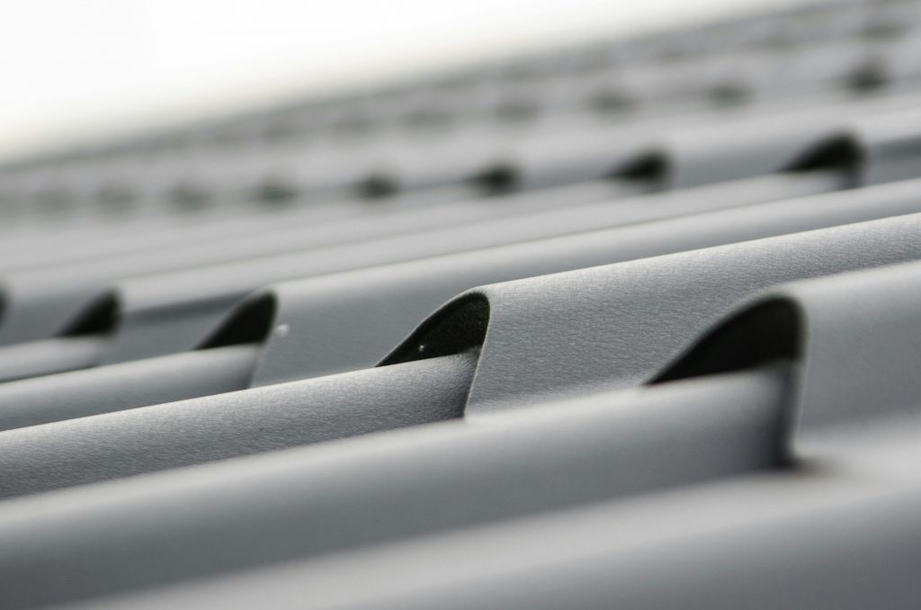 roof-plate-tiles-brick-black-48895-48895 Detailed close-up of grey metal roof sheets showcasing texture and design.